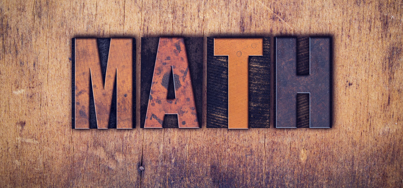 The letters for MATH in moveable type on a wooden background.